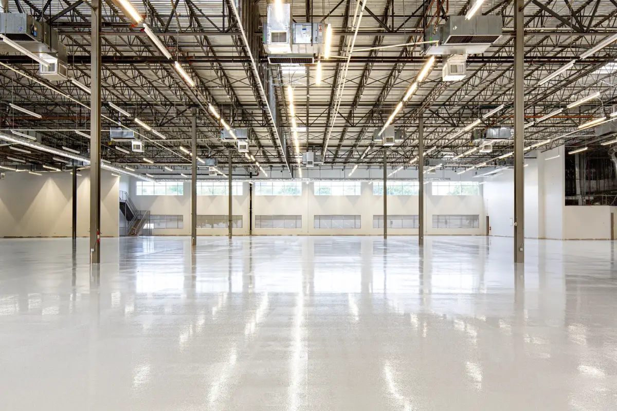 Glossy white high-build industrial epoxy floor under steel trusses